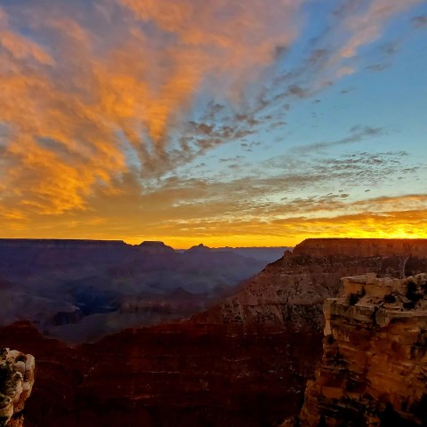 Grand Canyon at sunset with colorful sky and rocky cliffs.