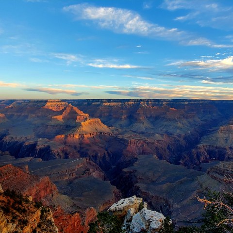 Sunset view of the Grand Canyon with colorful cliffs and a vast sky.