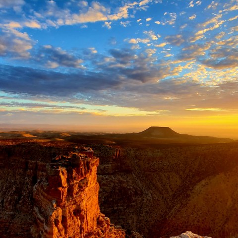 Scenic canyon view at sunset with vibrant sky and sun on the horizon.