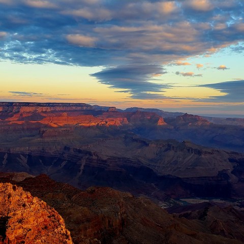 Grand Canyon at sunset with colorful clouds and rugged landscape.