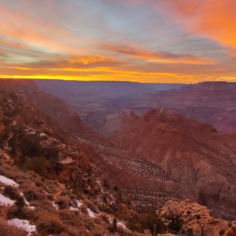 Sunset over the Grand Canyon with vibrant orange and pink sky hues.
