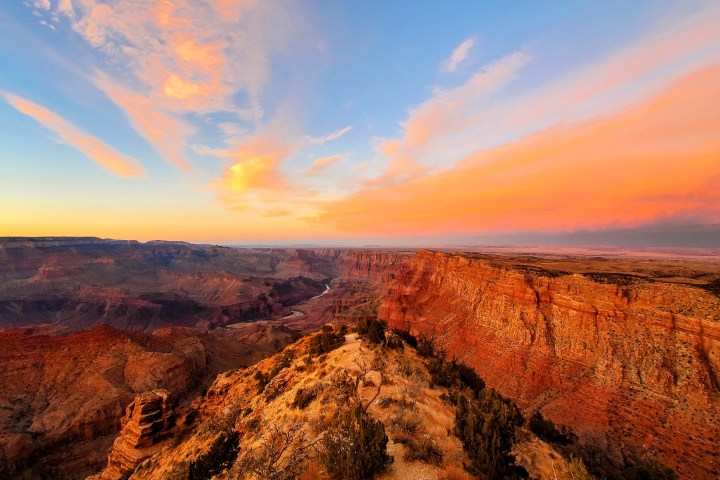 Canyon landscape at sunset with vibrant orange and pink clouds in the sky.