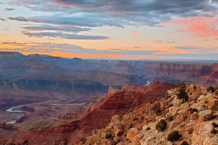 Grand Canyon view with colorful sky at sunset and a river below.