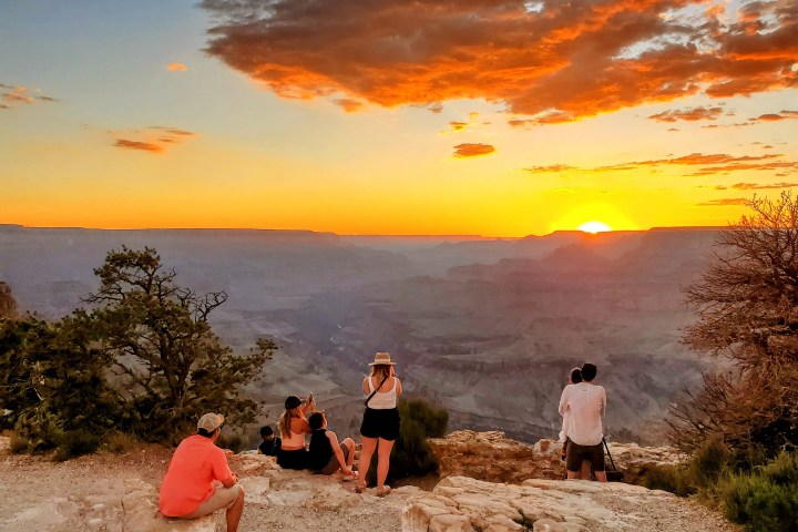 Group watching sunset over Grand Canyon with colorful sky.