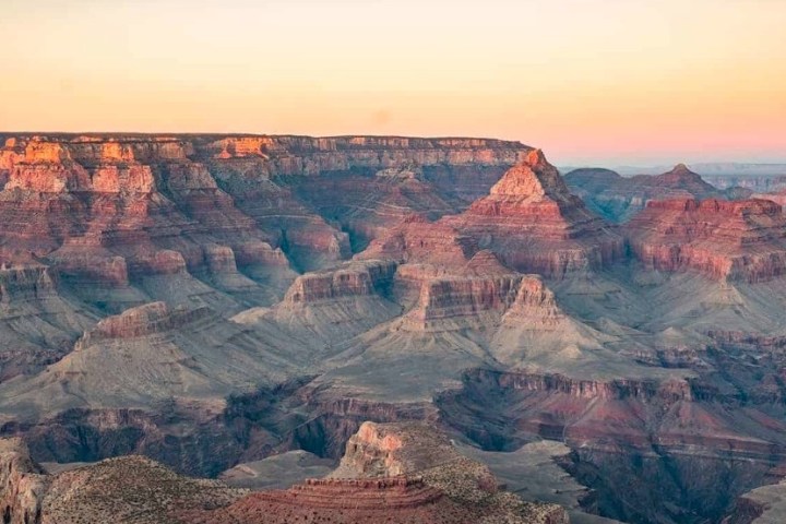 Grand Canyon landscape at sunset with colorful rock formations and a clear sky.
