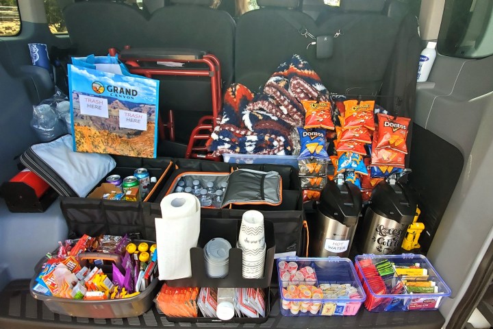 Van trunk with snacks, drinks, coffee, chips, and utensils organized for convenience.